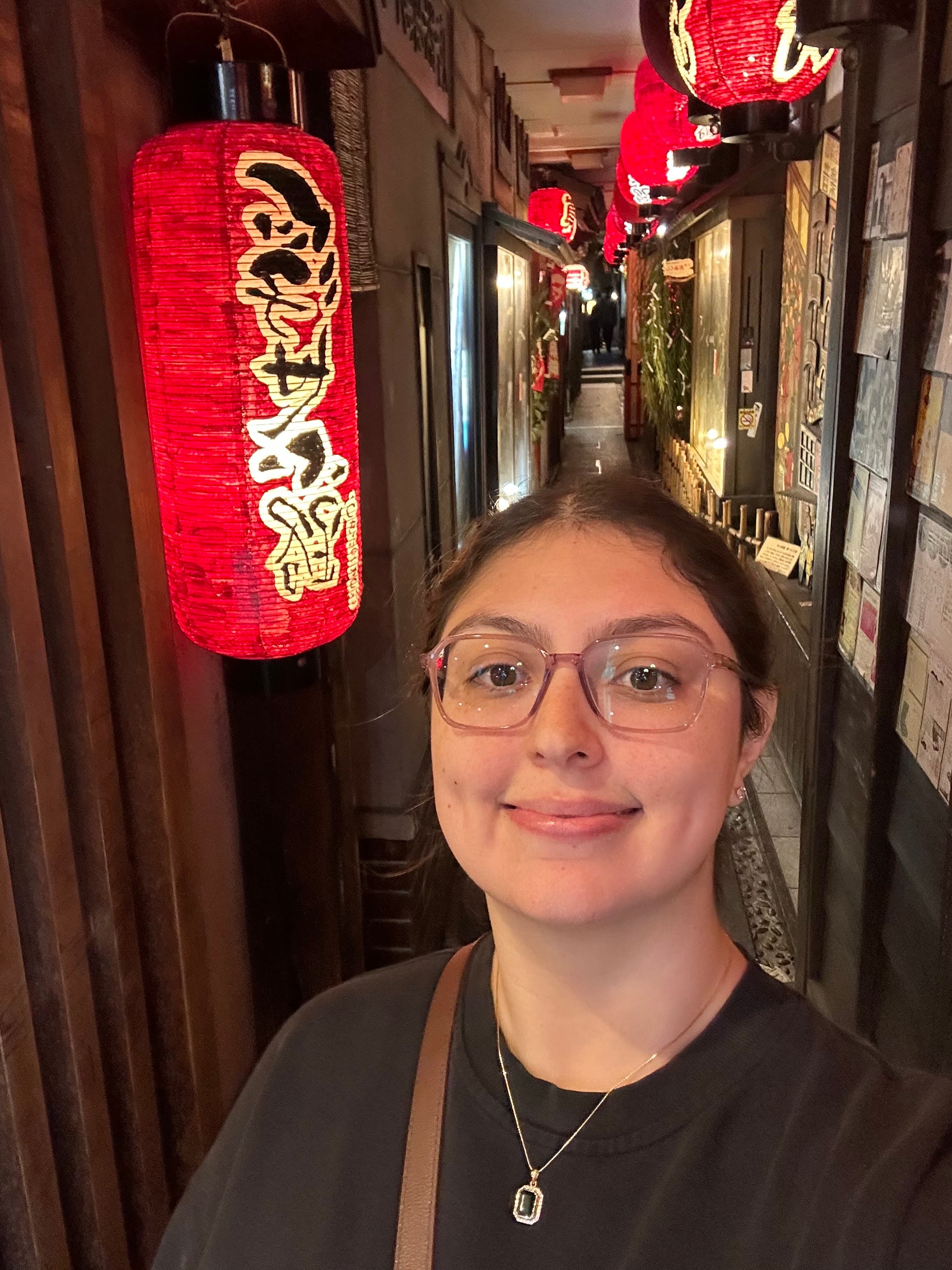 Portrait of Sarah Lutter smiling in a lantern-lit hallway.